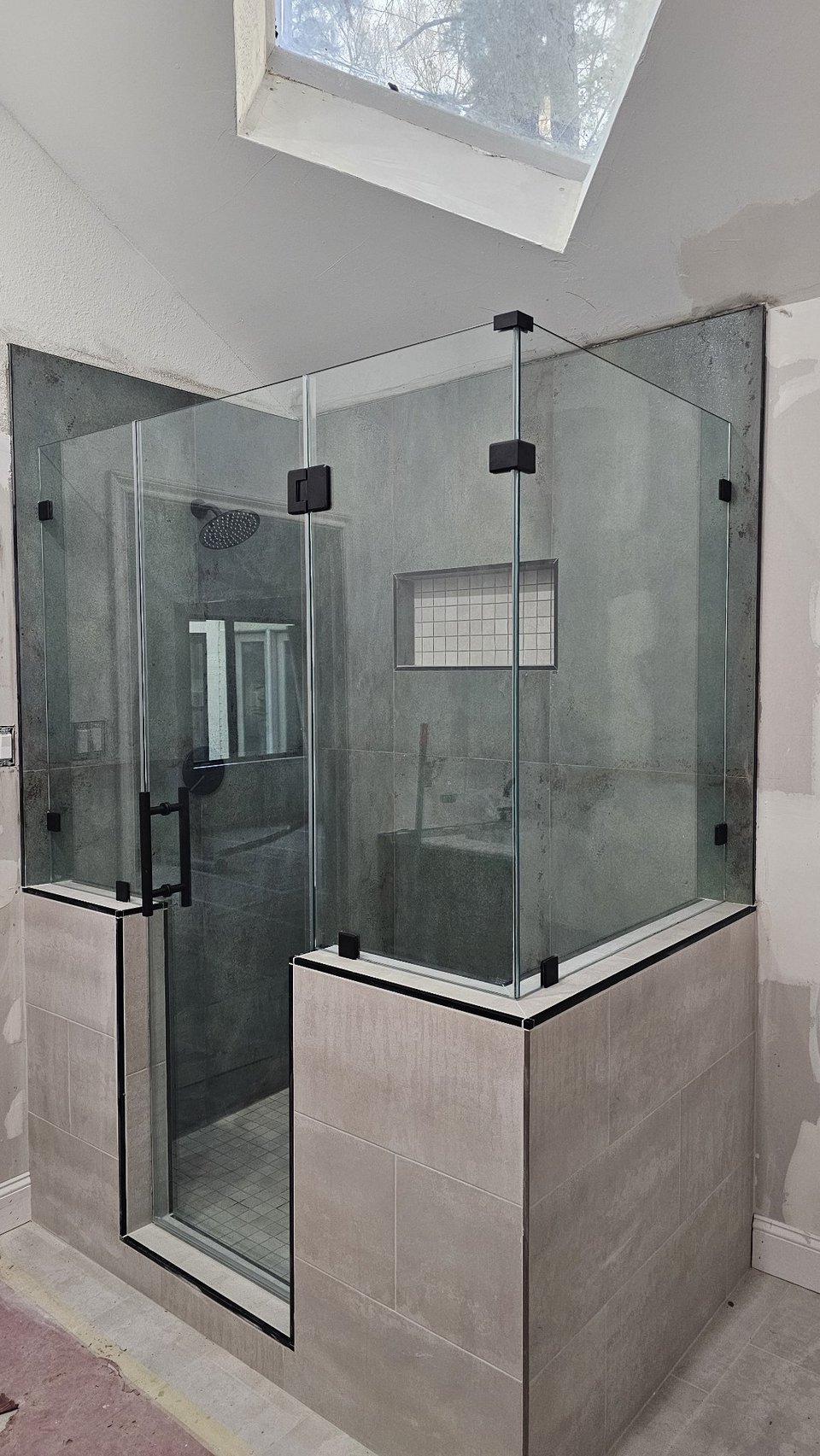 Glas Plus 90° angle over half walls example: clear glass mounted on half walls in a 90° corner, with black hardware