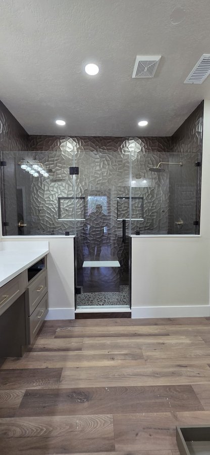 Glas Plus center hinged door over half walls example: center hinged door down to the floor and fixed glass panels on half walls on both sides, with black hardware