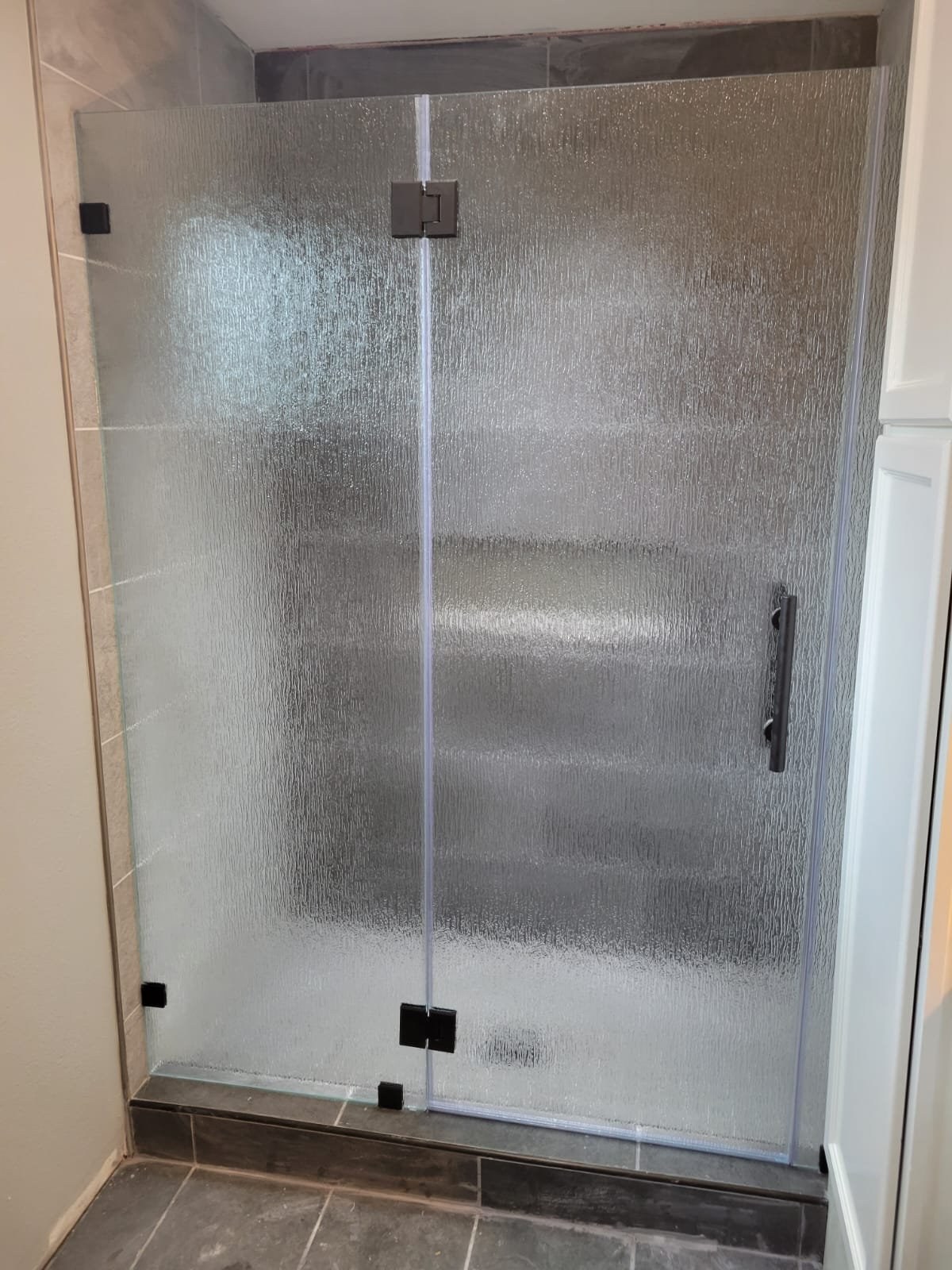 Glass-to-glass hinged door with Rain glass (rain texture) and black hardware