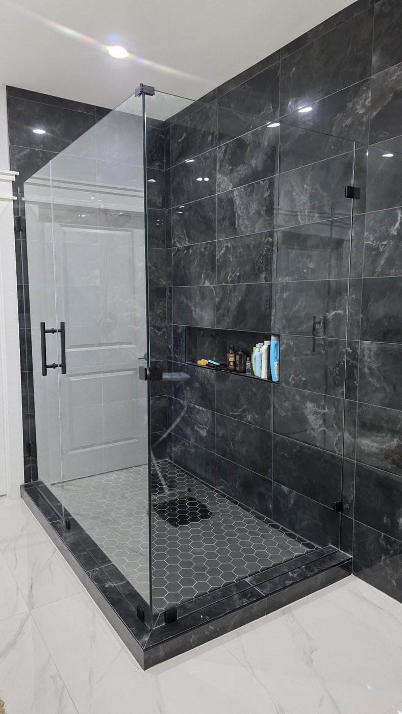 Glas Plus job: 90° angle with black hardware in a dark marble shower