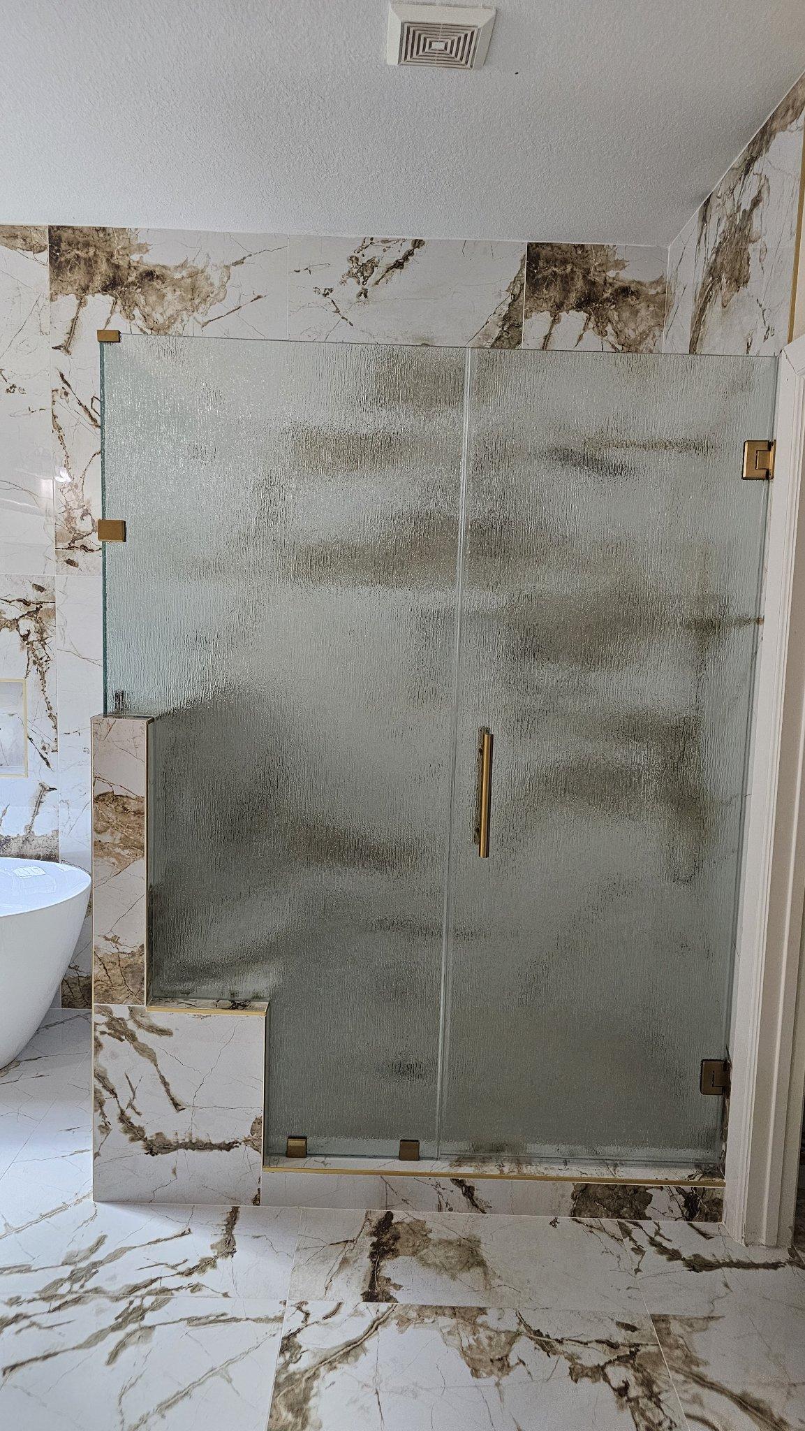 Glas Plus job: straight-line shower with Rain glass (rain texture), notch over a marble bench and gold hardware