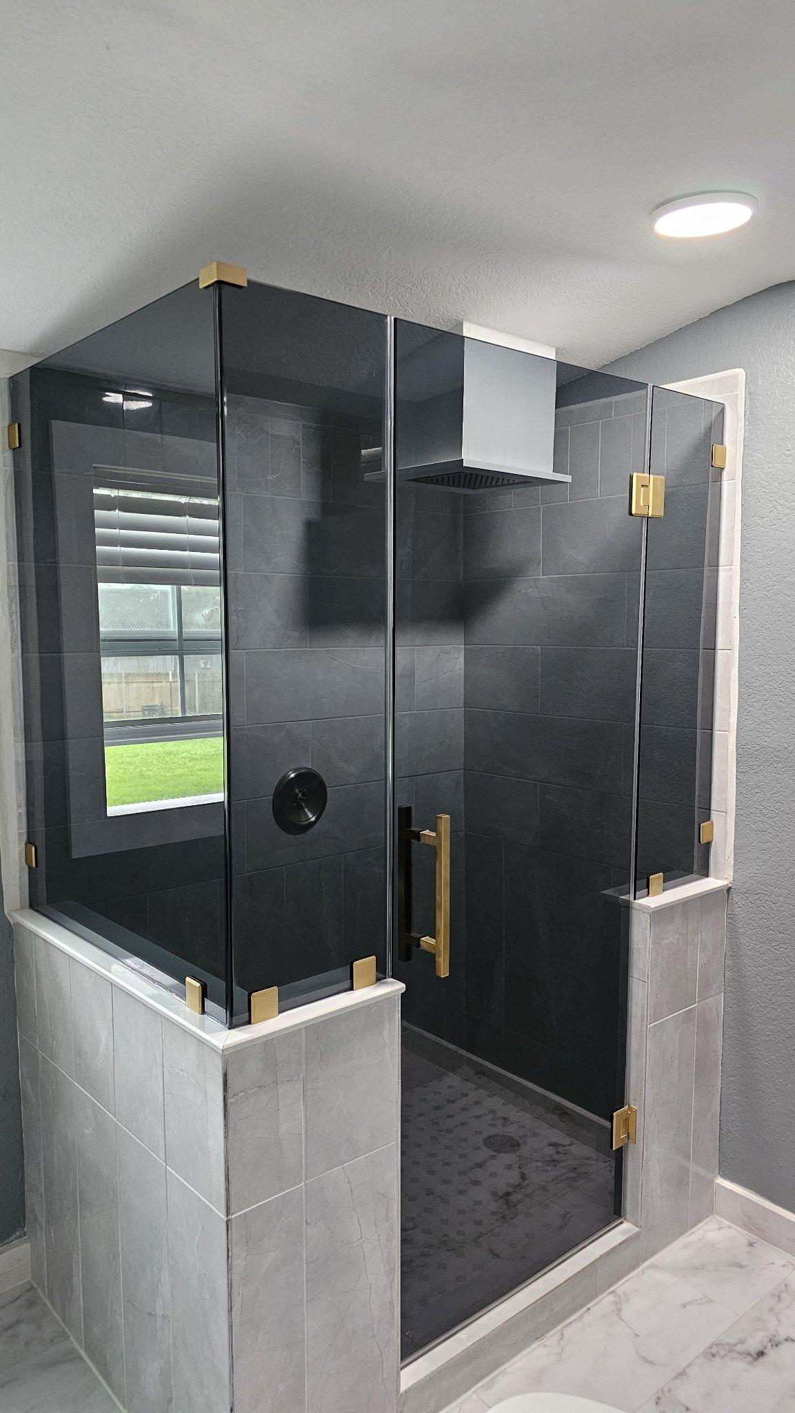 Glas Plus job: 90° angle shower with Grey glass (smoked grey) mounted on walls and gold hardware
