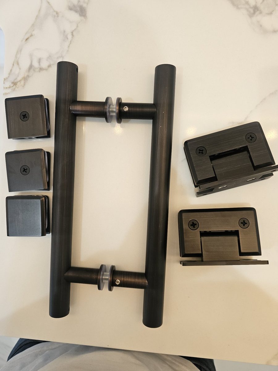 Complete Glas Plus dark bronze hardware set: handles, clips and hinges on a marble table