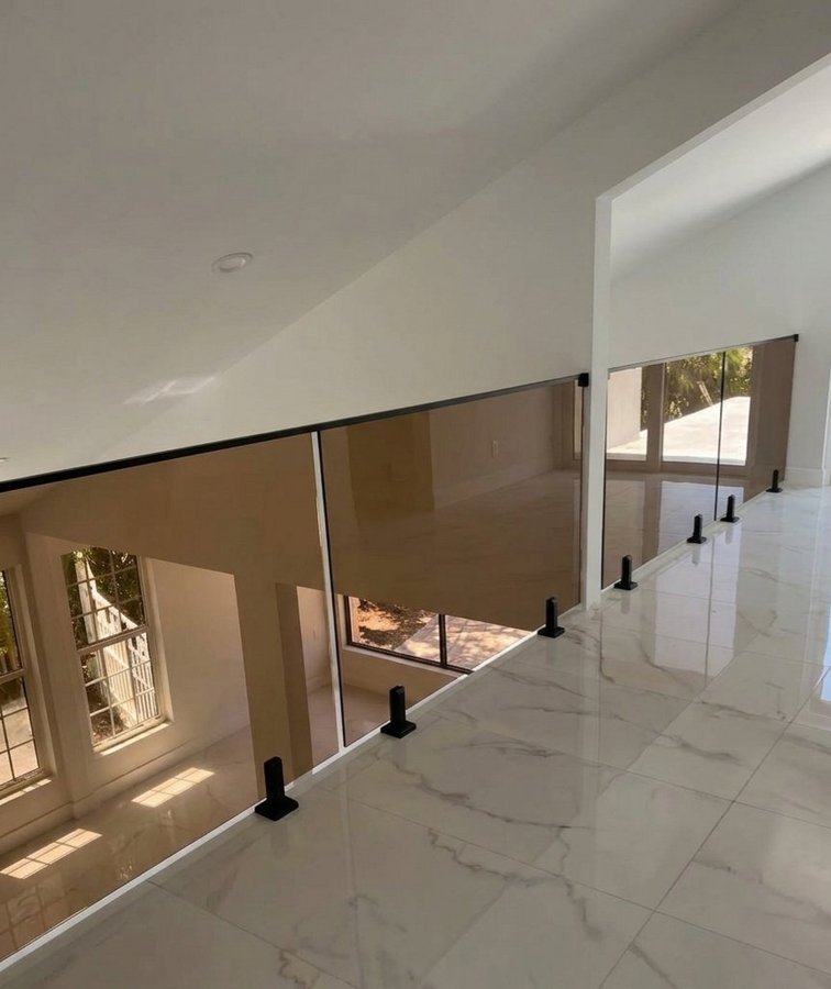 Glas Plus balconies example: smoked glass railing on a double-height interior balcony, with a marble floor
