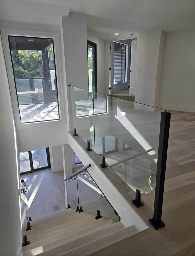Glas Plus staircases example: glass railing on a staircase and upper landing, with black posts and hardware