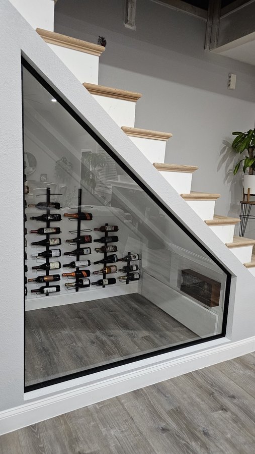 Glas Plus special orders example: wine cellar under the stairs closed off with a triangular glass panel with a black frame