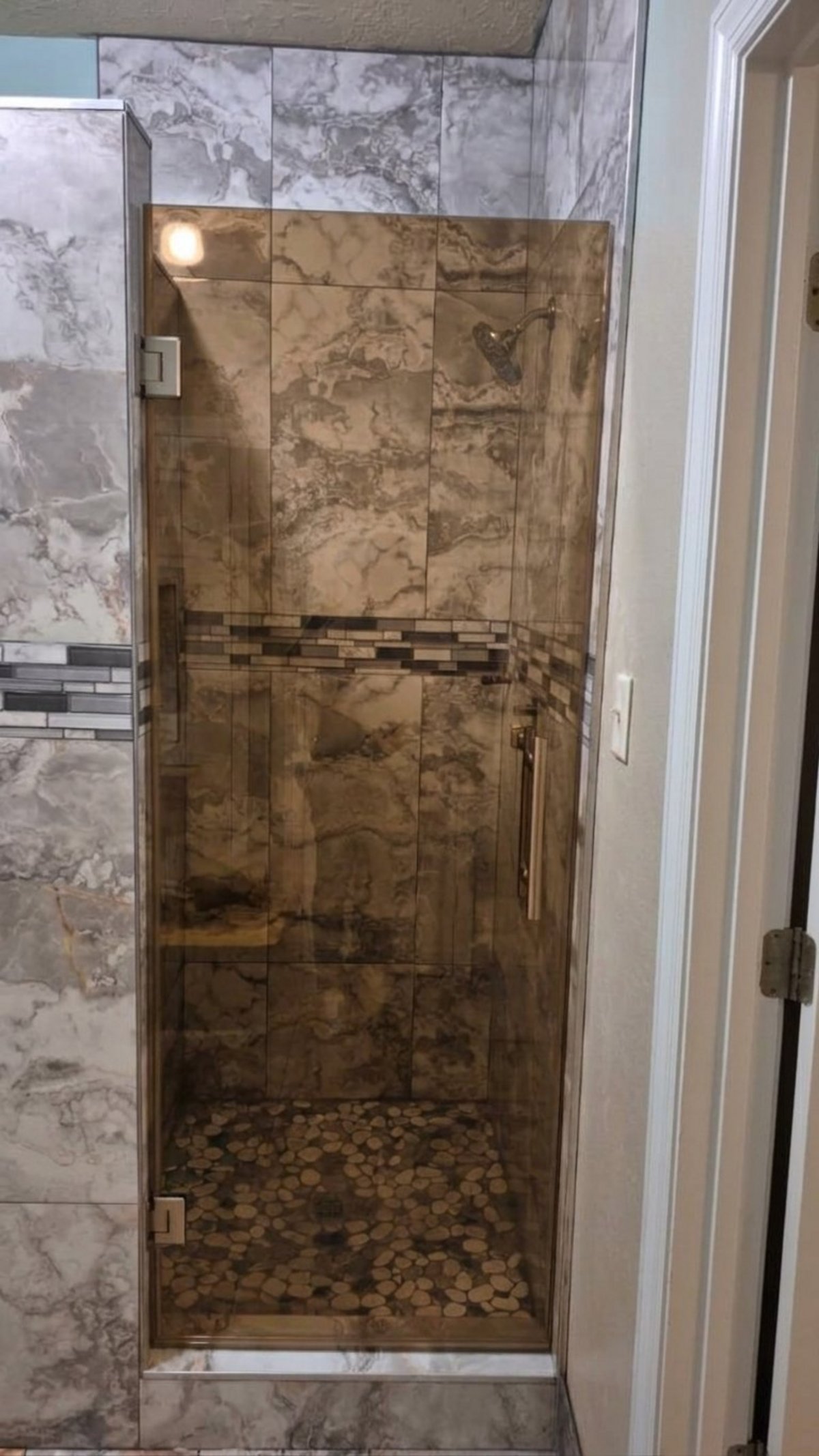 Single door with Bronze glass (bronze tone) and brush nickel hardware installed by Glas Plus in a marble-look tile shower