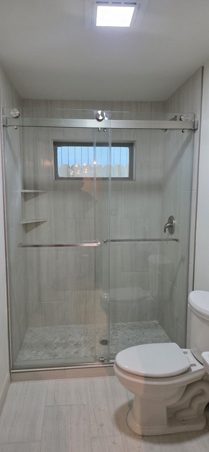 Double-door sliding with chrome track in a subway tile shower with a niche