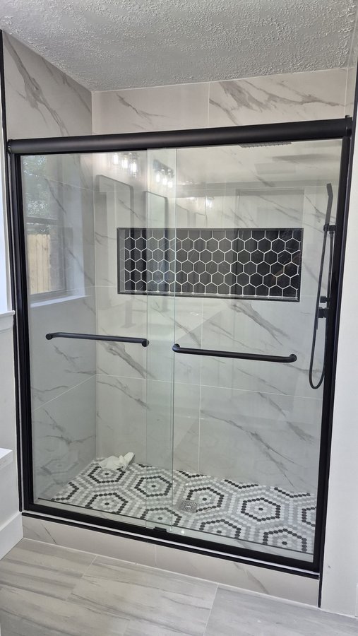 Double-door sliding with a black frame in a light geometric tile shower