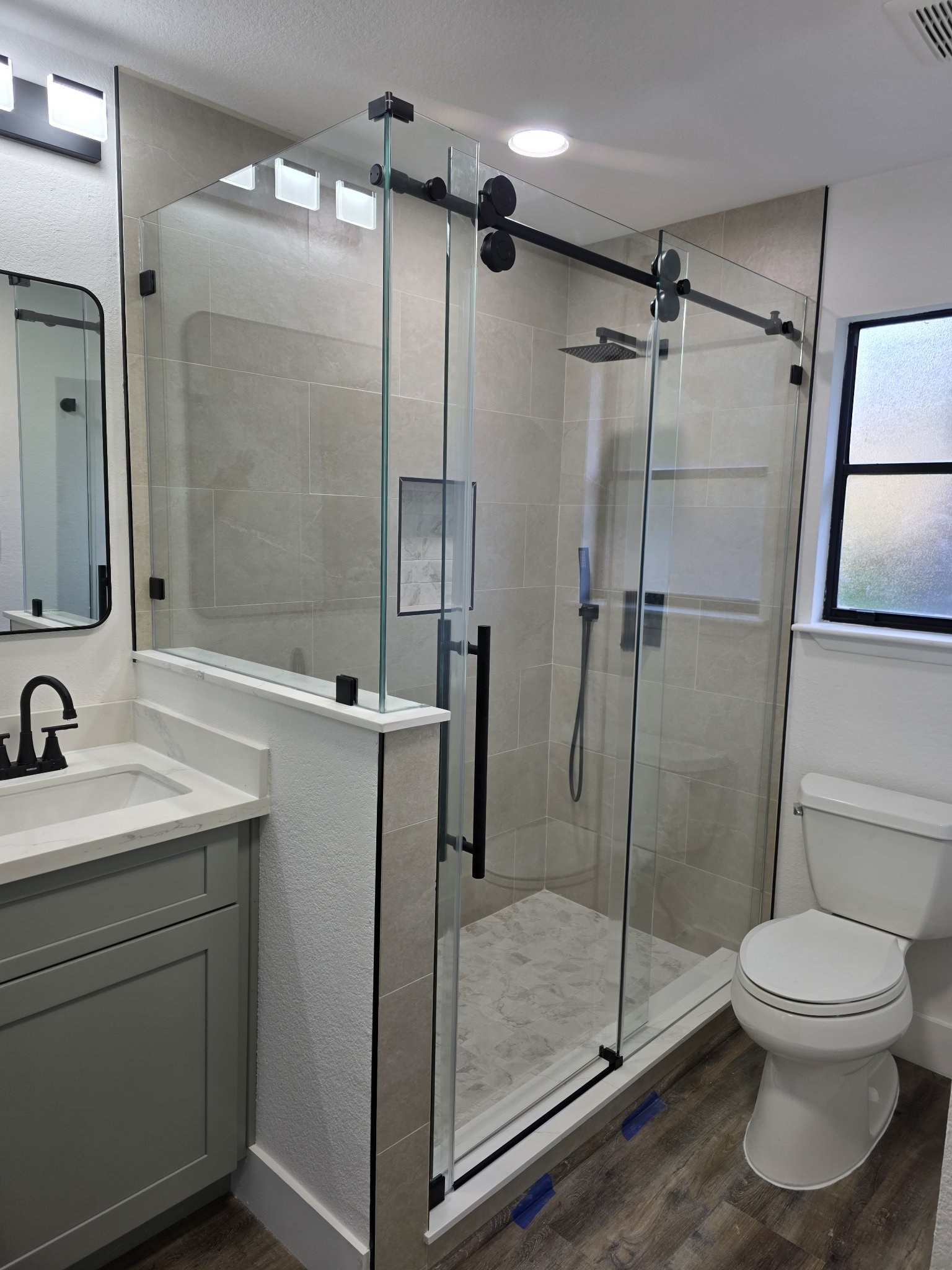 Sliding with return over a half wall with a black track in a beige tile shower