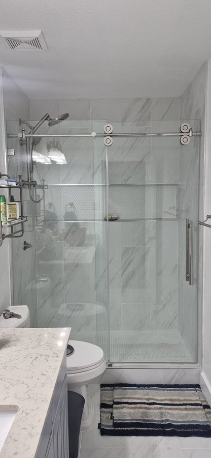 One-door sliding with chrome track and fixed panel in a dark tile shower