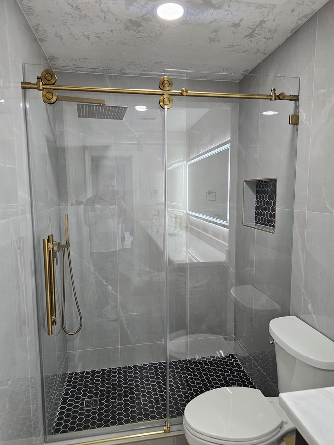 One-door sliding with gold track and towel bar in a shower with a niche