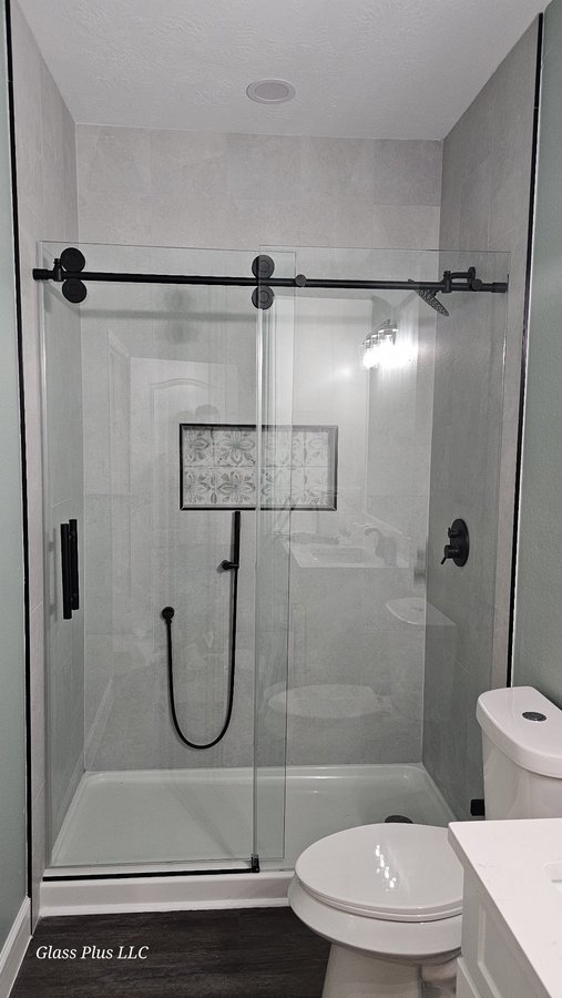 One-door sliding with black track and fixed panel in a grey tile shower